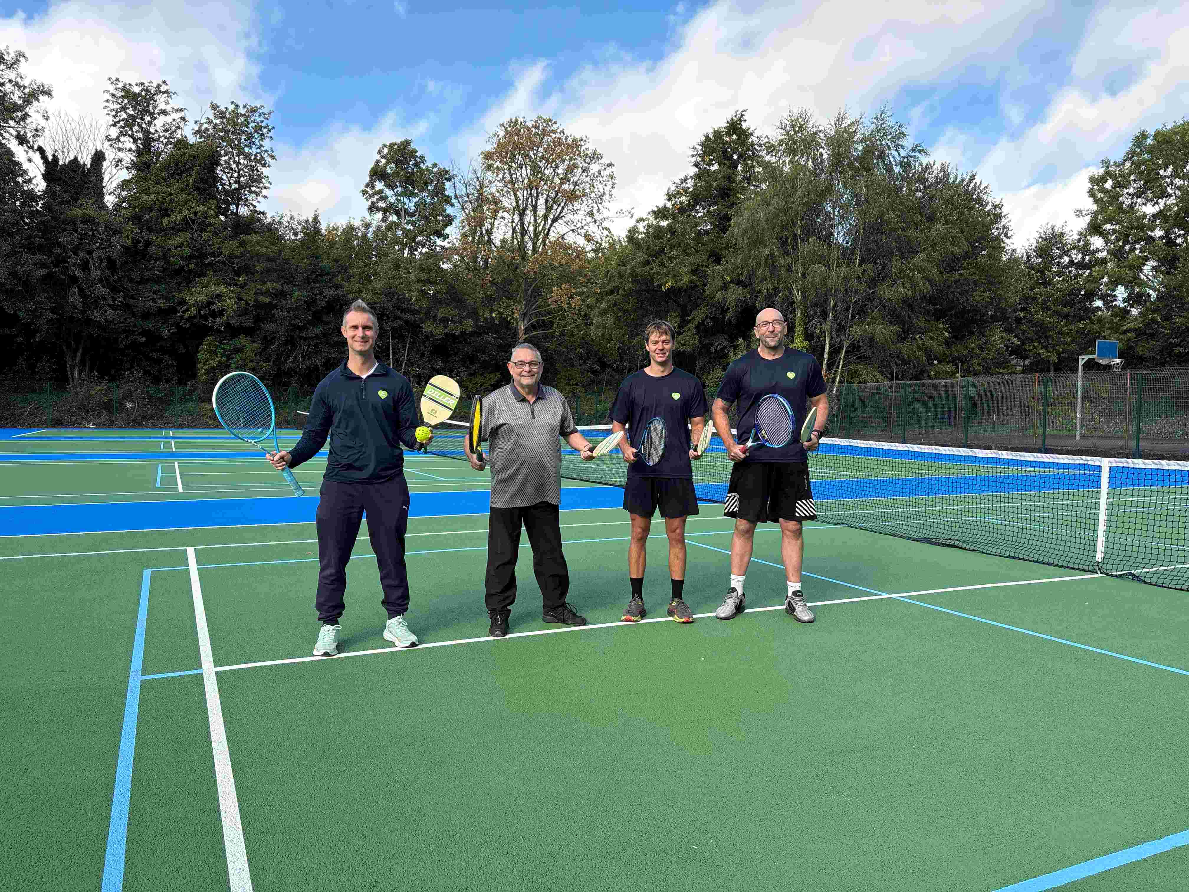 Four people standing on the new court Four people standing on the new court